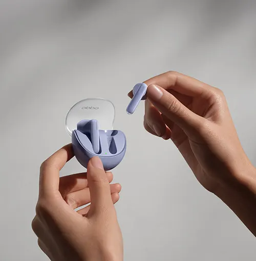 Mani che tengono auricolari viola con custodia aperta su sfondo chiaro. Un auricolare � tenuto separatamente.