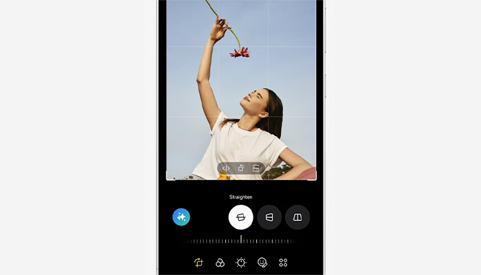 Una donna tiene un fiore rosso su uno sfondo azzurro, visualizzata in un'app di editing con opzioni di raddrizzamento.