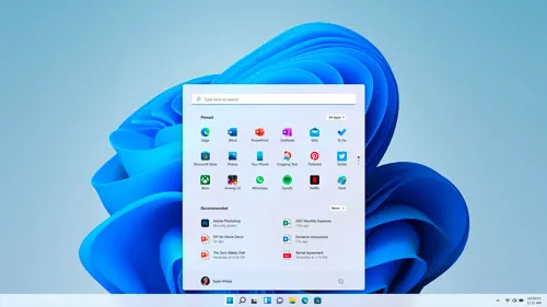 Schermata di Windows 11 con menu Start aperto su sfondo blu astratto. Icone app e consigli visibili.