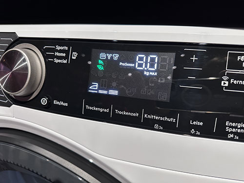 Pannello comandi bianco di una lavatrice con display digitale che indica 8.0 kg MAX, manopola, e pulsanti vari.