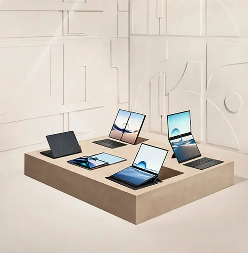 Sette computer portatili su un espositore beige. Alcuni hanno schermi blu, altri sono chiusi. Lo sfondo � bianco.