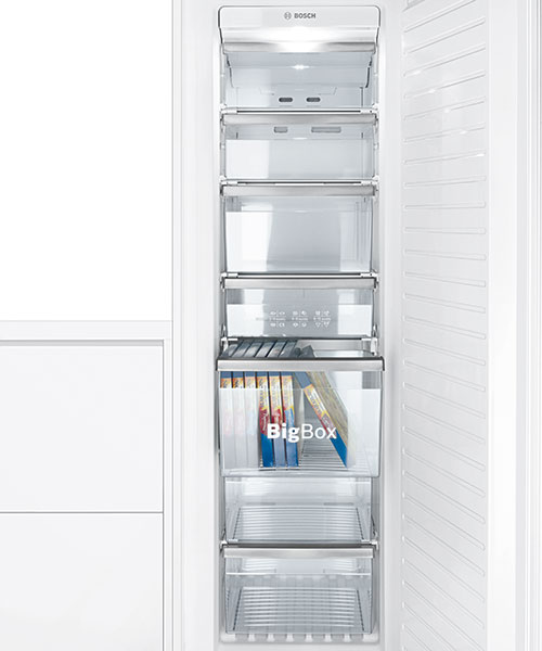 Frigorifero bianco aperto con cassetti trasparenti, alcuni pieni di alimenti confezionati.