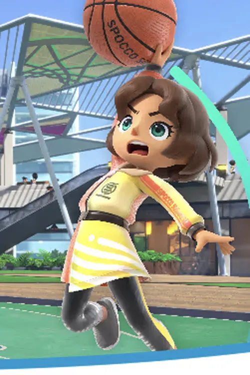 Ragazza in tenuta sportiva gialla tiene un pallone da basket su un campo verde, con tribune sullo sfondo.