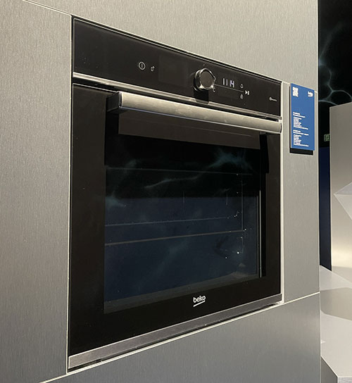 Forno nero incassato nel mobile grigio, con maniglia orizzontale argentata. Pannello di controllo in alto con display digitale.