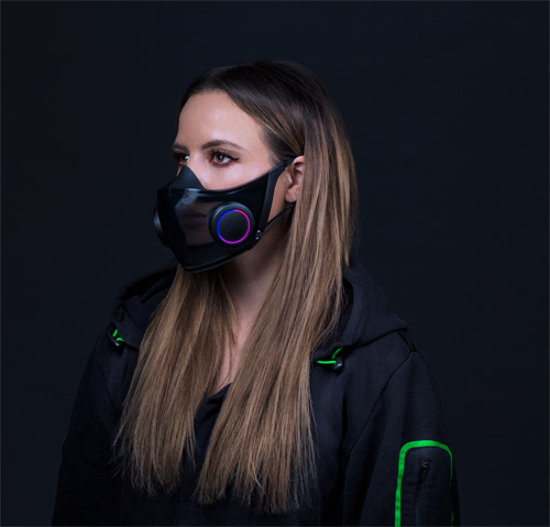 Donna che indossa una maschera nera con dettagli viola e blu, e una felpa nera con linee verdi. Lo sfondo � nero.