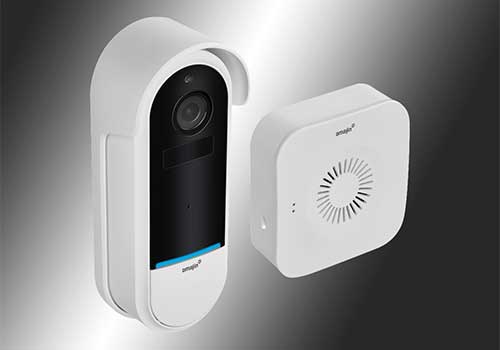 Telecamera di sicurezza bianca con lente nera, montata a parete con altoparlante quadrato bianco su sfondo grigio.