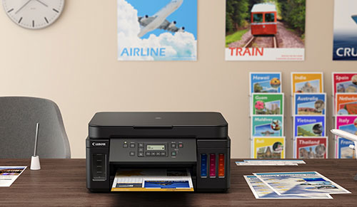Scrivania con stampante Canon, brochure e orologio a muro. Sullo sfondo, poster di viaggi con aereo, treno e crociera.