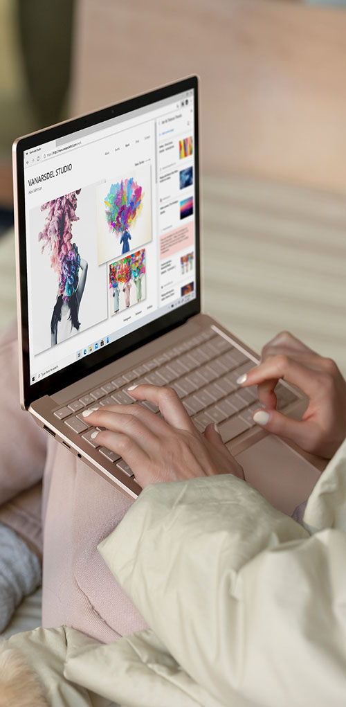 Mani digitano su un laptop color oro con schermo che visualizza il sito "Vanarsdel Studio" su uno sfondo neutro.