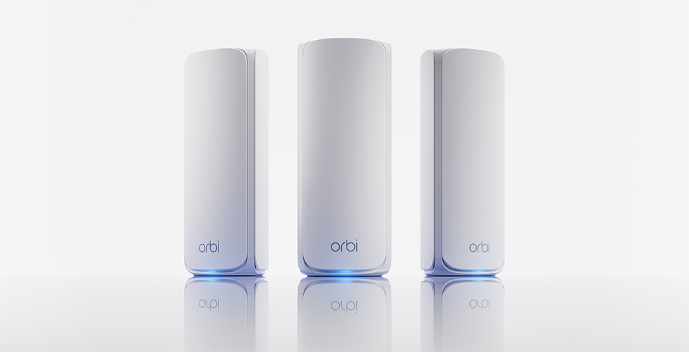 Tre dispositivi bianchi cilindrici "orbi" allineati su una superficie lucida bianca riflettente con sfondo bianco.