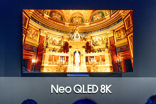 Schermo TV con immagine di interno di chiesa dorata. Testo "Neo QLED 8K" in basso. Sfondo blu scuro.