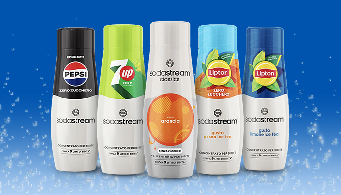 Quattro bottiglie di sciroppo Sodastream: arancione, arancia Mirinda, blu Pepsi e verde 7up su sfondo azzurro con gocce.