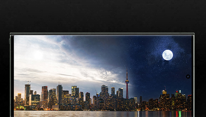 Schermo con skyline di citt� diviso tra giorno e notte, luna piena visibile. Grattacieli illuminati e riflessi sull'acqua.