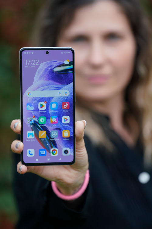 Donna che tiene un telefono con icone di app su sfondo verde.