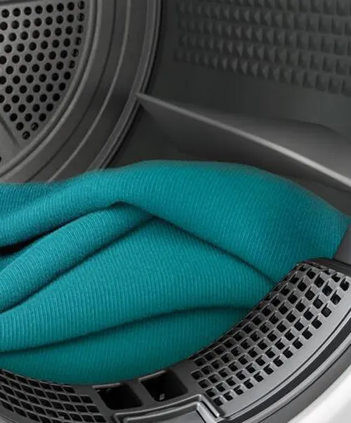 Interno asciugatrice grigia con un indumento piegato di color turchese. Il tamburo � forato.