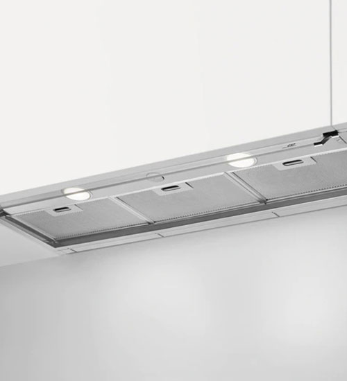 Cappa da cucina argentata con luci integrate e filtri rettangolari, appesa a un soffitto bianco.