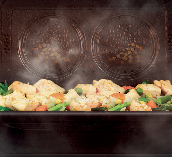 Pollo e verdure miste, come carote e fagiolini, cotti al vapore in una vaporiera nera.