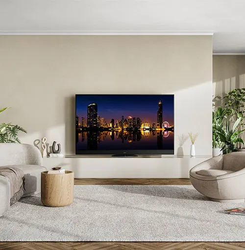 Salotto con TV che mostra uno skyline urbano notturno, divano bianco e poltrona rotonda su tappeto grigio.