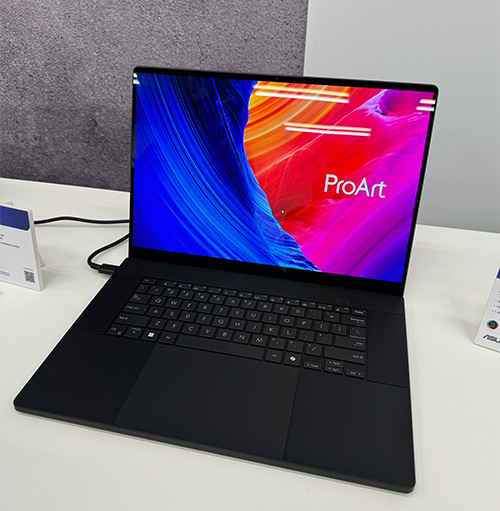 Un computer portatile nero aperto mostra la scritta "ProArt" su uno schermo con sfondo blu, arancione e rosa.