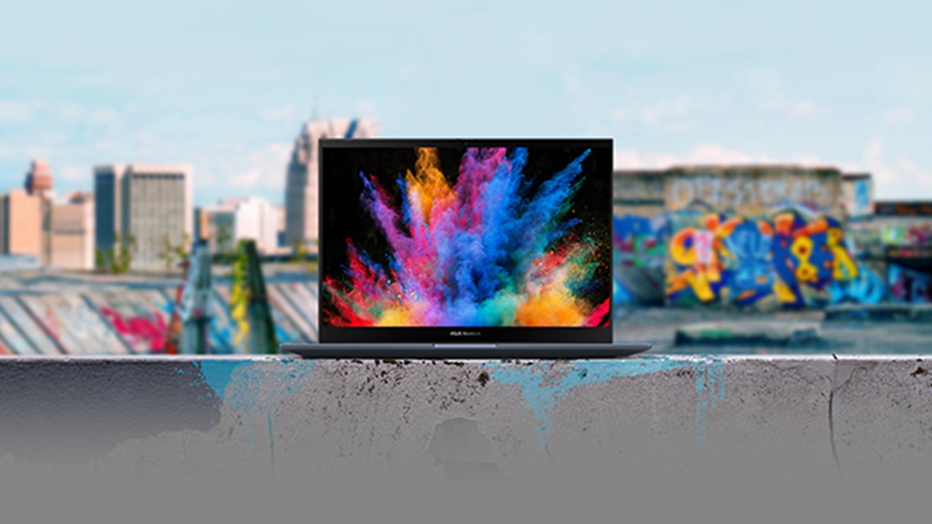 Città sullo sfondo di un laptop aperto su un muro. Lo schermo del laptop è nero con una grafica colorata.