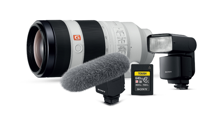 Obiettivo, microfono, scheda di memoria e flash Sony su sfondo bianco. L'obiettivo è bianco con dettagli neri.