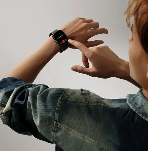 Primo piano di un uomo che interagisce con uno smartwatch nero al polso, indossa una giacca di jeans.