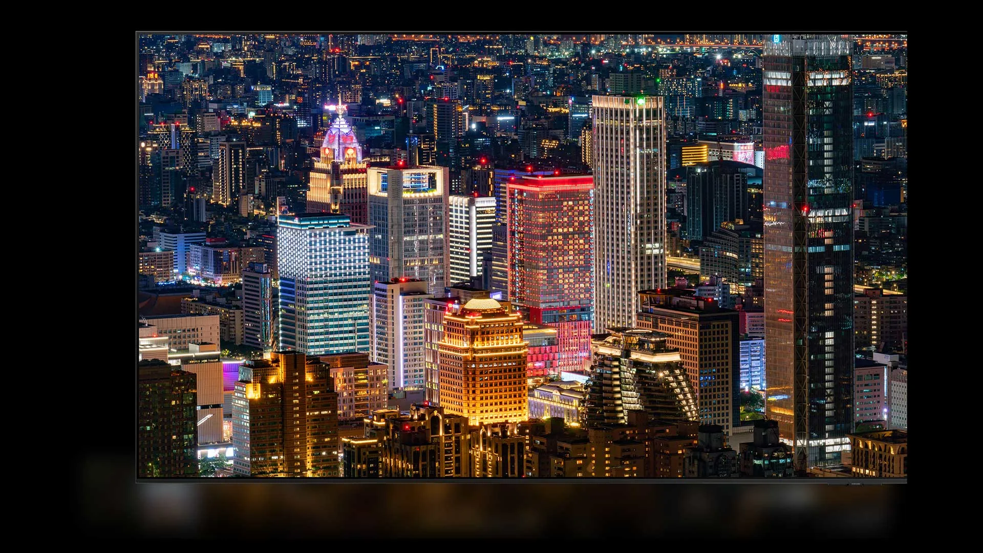 Veduta notturna di una città con grattacieli illuminati di bianco, rosso e giallo.