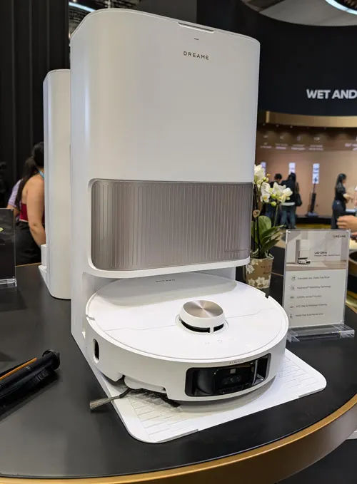 Robot aspirapolvere bianco su base bianca, con stazione di ricarica bianca e dettagli grigi su un tavolo nero.