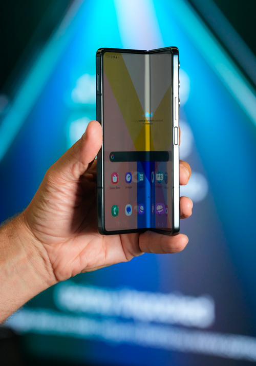 Una mano tiene un telefono pieghevole aperto con icone sullo schermo. Lo sfondo � blu.