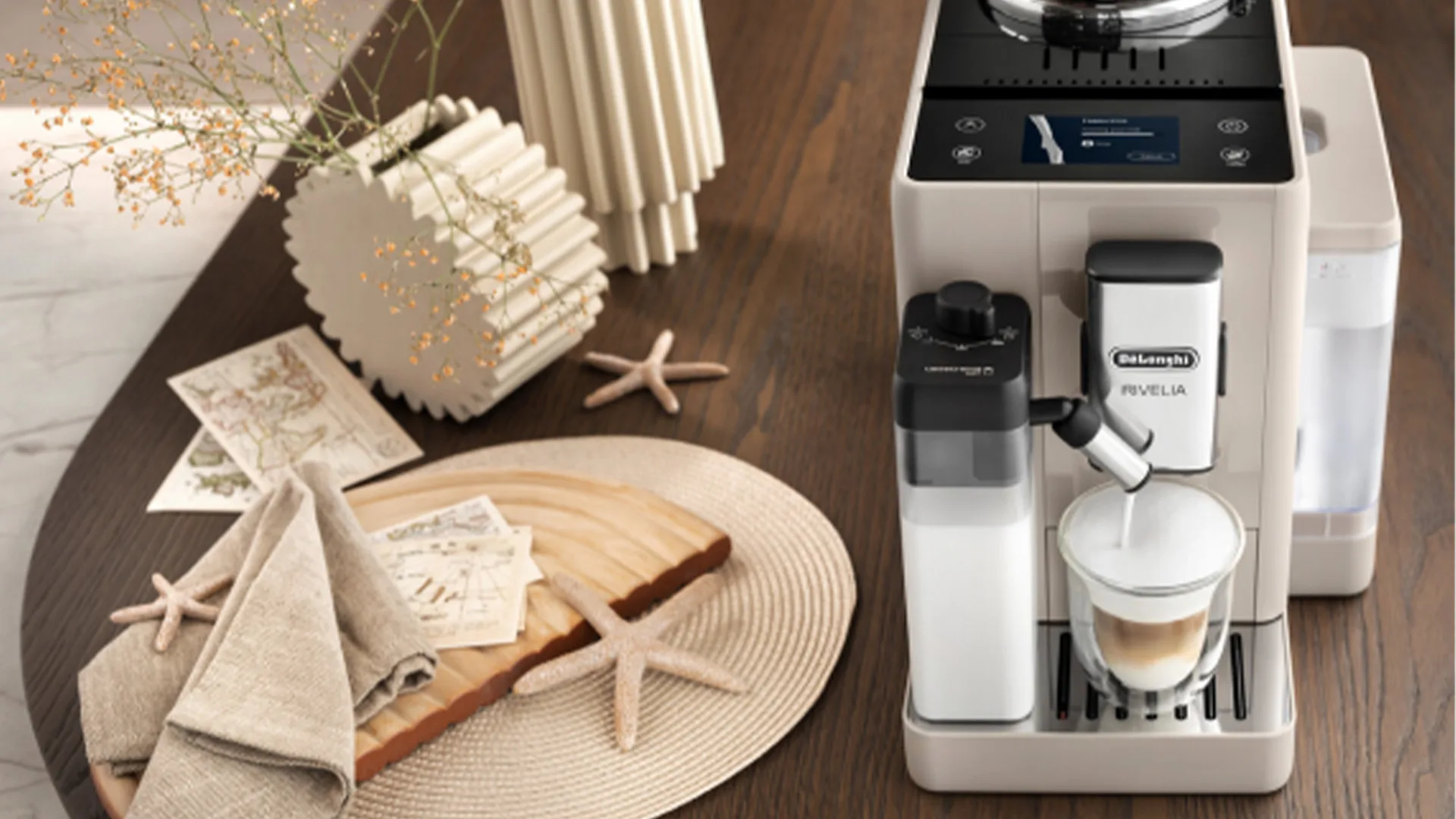 Macchina da caff� beige con latte. Sul tavolo, decorazioni con stelle marine, fiori e cartoline.