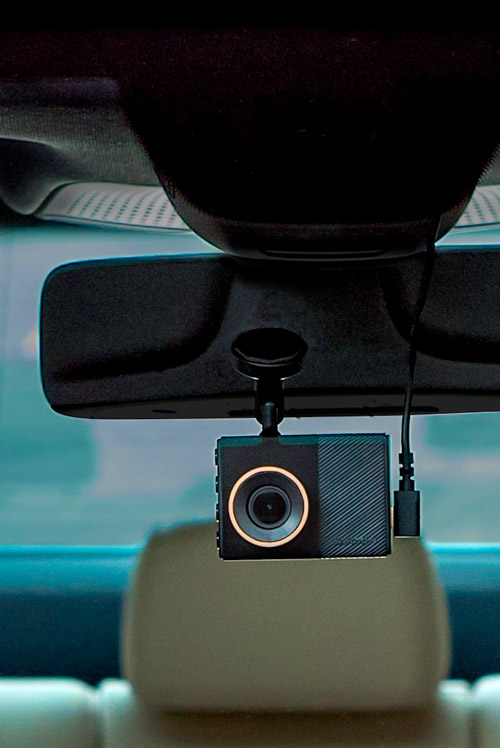 Telecamera nera montata su uno specchietto retrovisore in auto. Un cavo � collegato alla fotocamera. Sedile auto sullo sfondo.