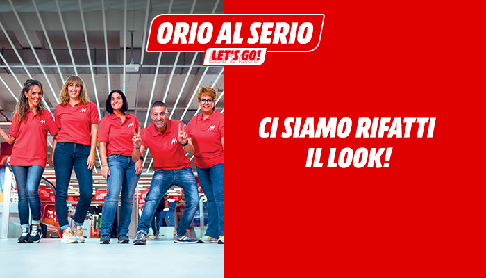 Cinque persone in magliette rosse e jeans davanti a uno sfondo rosso con testo e logo "Orio al Serio Let's Go!".