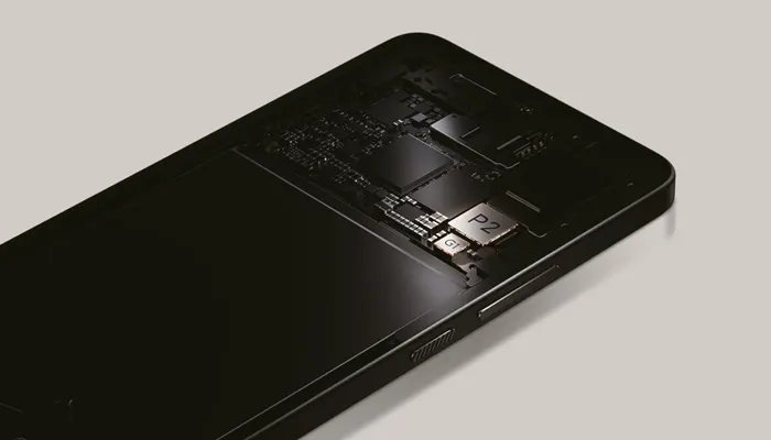 Un telefono nero mostra circuiti interni e componenti su sfondo grigio chiaro.