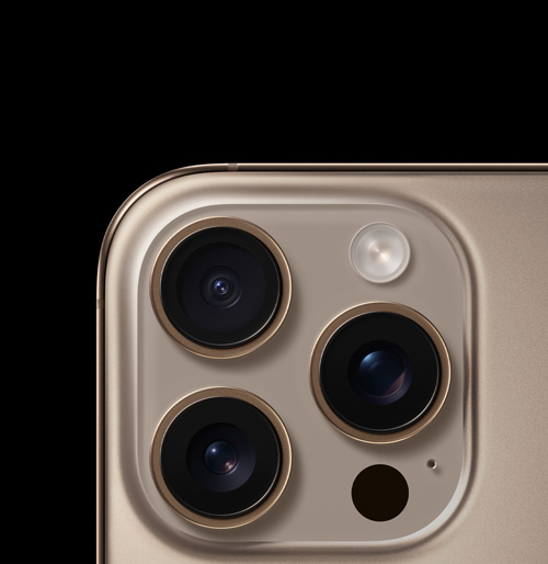 Primo piano di un telefono color oro con tre obiettivi della fotocamera, un flash e un microfono. Lo sfondo è nero.