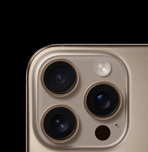 Primo piano di un telefono color oro con tre obiettivi della fotocamera, un flash e un microfono. Lo sfondo è nero.