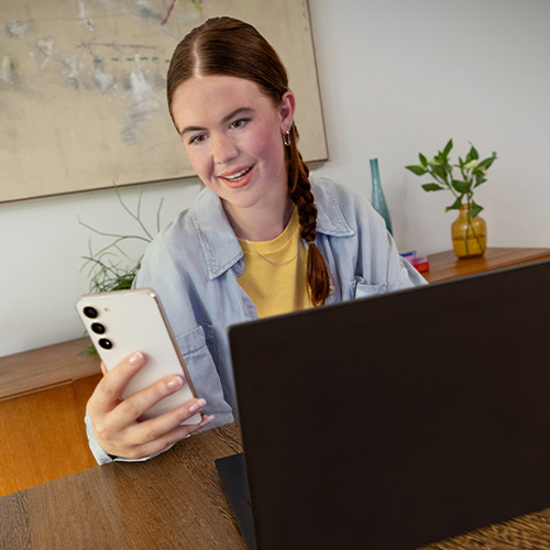Due donne guardano un laptop. Una indossa una polo rossa, l'altra una giacca a quadri e una maglia verde.