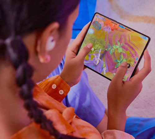 Ragazza con cuffie che gioca a videogioco su tablet con sfondo blu e arancione.