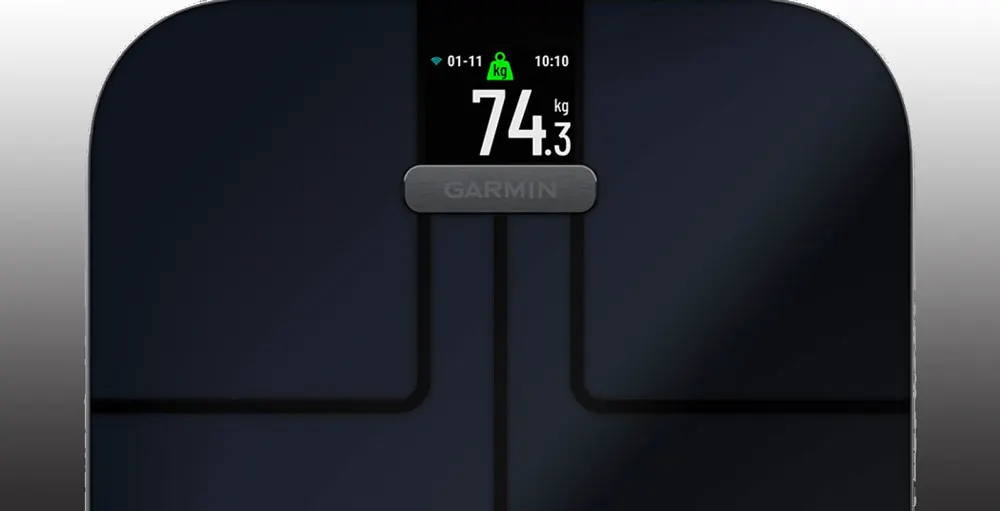 Bilancia digitale nera con schermo che indica un peso di 74.3 kg, data 01-11, ora 10:10 e logo Garmin.