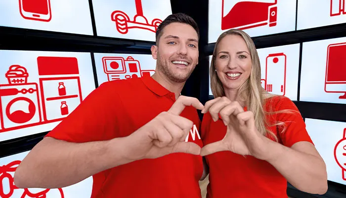 Uomo e donna sorridono, formando un cuore con le mani. Indossano magliette rosse davanti a schermi con icone di prodotti bianchi e rossi.