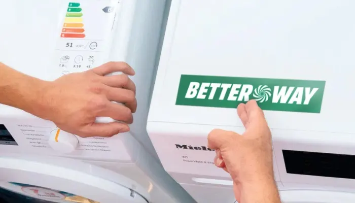 Lavatrice bianca Miele con etichetta verde "BETTER WAY". Una mano regola il selettore.