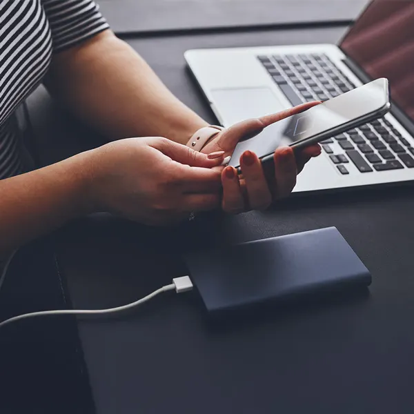 una donna mentre mette sotto carica il suo smartphone