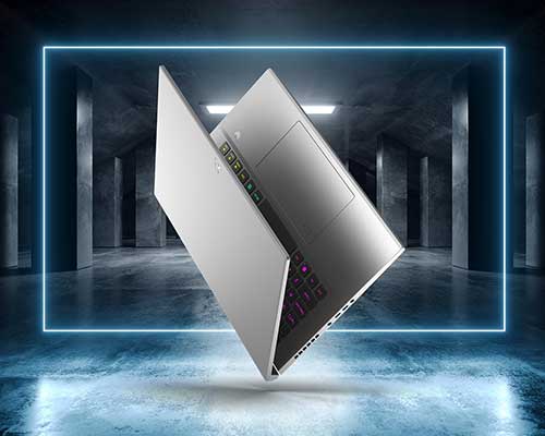 Un portatile grigio fluttua su un pavimento grigio, con uno sfondo di colonne grigie e un rettangolo di luce blu.