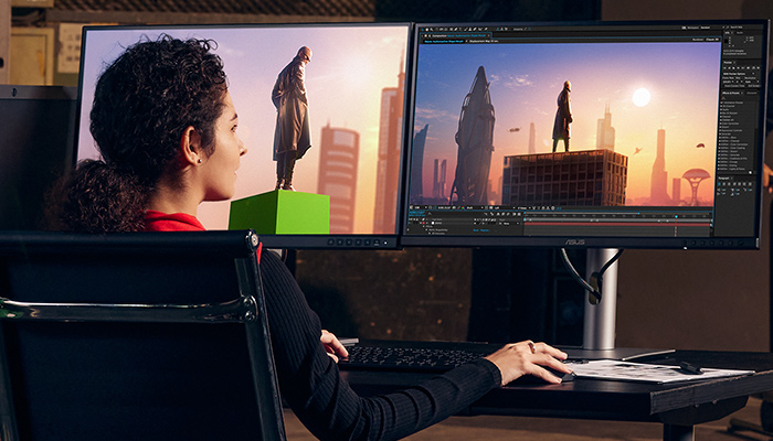 Donna seduta davanti a due monitor che mostrano personaggi su edifici in una citt� futuristica.