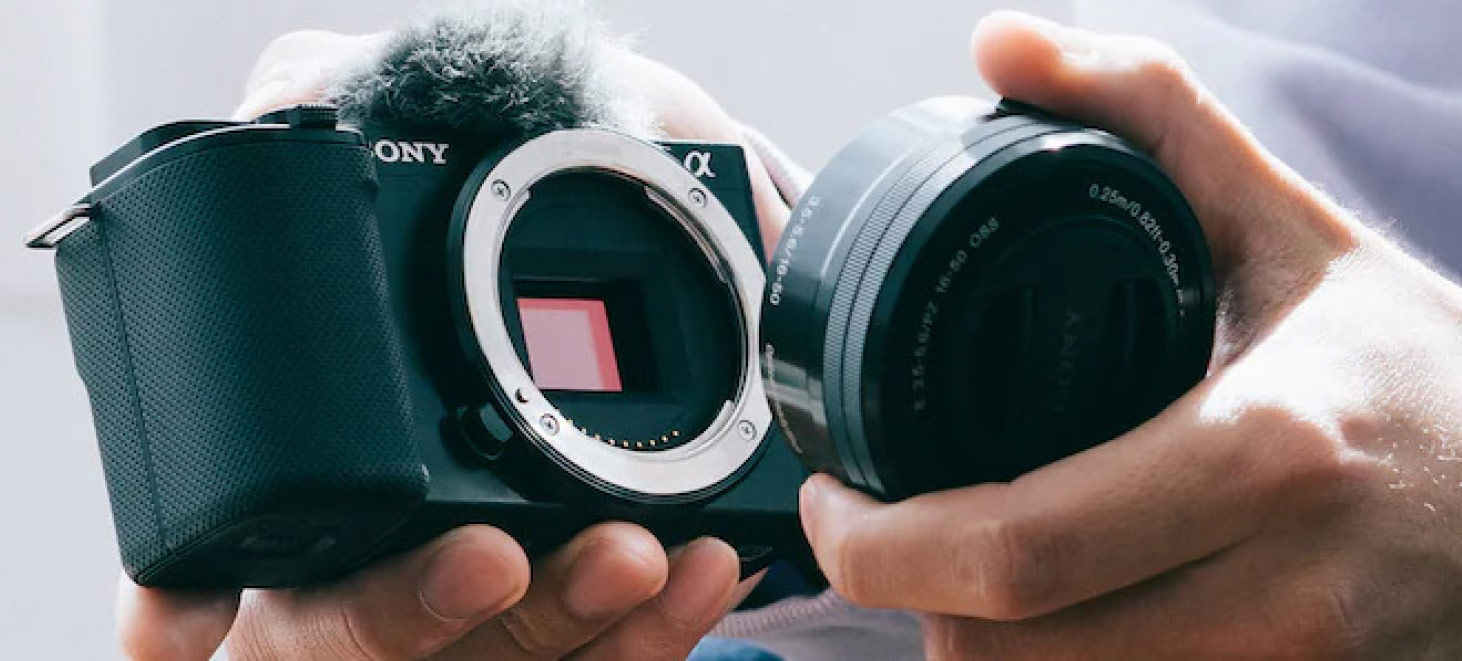 Un obiettivo nero viene montato su una fotocamera Sony nera tenuta in mano.
