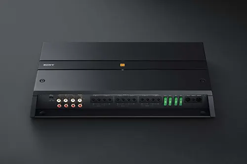 Amplificatore nero con connettori rossi, bianchi e verdi su sfondo scuro.