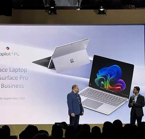 Presentazione di un laptop Surface su un palco con due persone e una folla sullo sfondo.