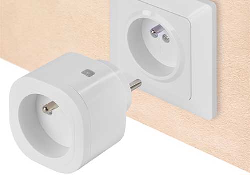 Presa bianca a muro con adattatore bianco inserito. La parete è beige chiaro.