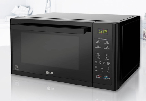 Forno a microonde nero su un ripiano bianco. Il display digitale mostra "12:30".