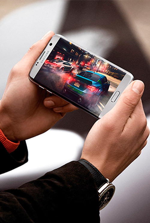 Mani che tengono un telefono che mostra una corsa di auto. Un orologio � al polso.