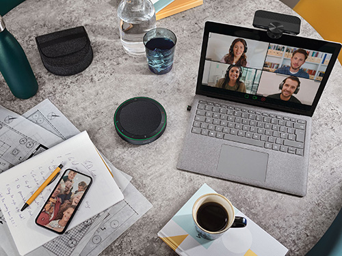 Scrivania con laptop in videochiamata, telefono, tazza di caff�, bottiglia d'acqua e documenti sparsi.