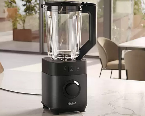 Frullatore nero con caraffa trasparente su un piano di marmo. Sullo sfondo, una finestra e arredi interni.
